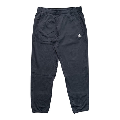 Dark gray athletic jogger pants with a textured waffle fabric, elastic waistband, side pockets, and a small white triangular logo on the left hip.