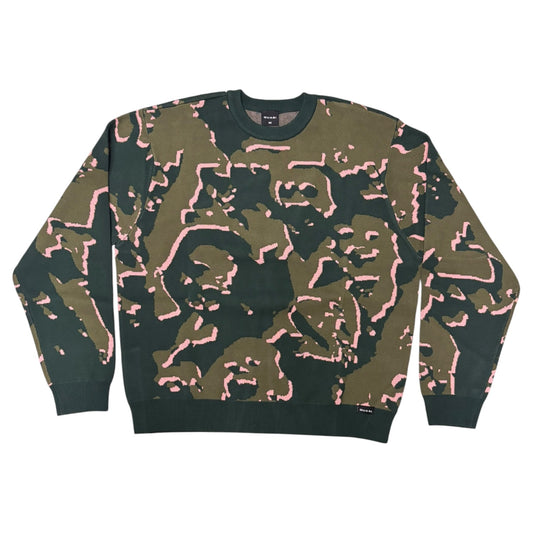 A crewneck sweatshirt featuring an abstract camouflage pattern in olive green, black, and light pink, laid flat against a white background.