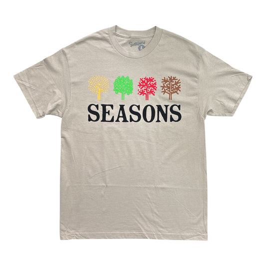 A light heather gray t-shirt featuring a graphic of four stylized trees in yellow, green, red, and brown above the word 'SEASONS' in black. The brand 'Seasons' is visible on the inner neck label.