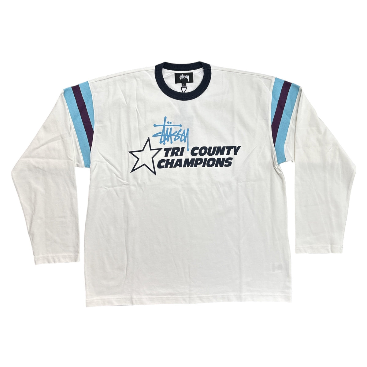 A vintage long-sleeve triathlon shirt by Stüssy, featuring a white body, navy blue collar and 'TRI COUNTY CHAMPIONS' text, light blue and navy stripe details on the sleeves, and a Stüssy logo.